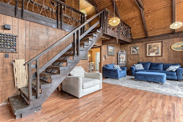 living room with beamed ceiling, high vaulted ceiling, wood walls, and wooden ceiling