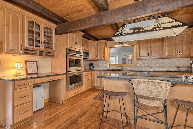 kitchen featuring beamed ceiling, wood finished floors, appliances with stainless steel finishes, a breakfast bar area, and glass insert cabinets