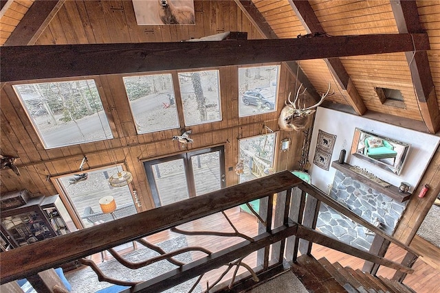 stairs featuring beam ceiling, wood walls, high vaulted ceiling, and wood ceiling