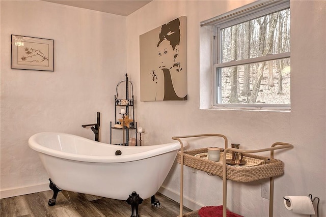 bathroom featuring wood finished floors, baseboards, and a freestanding bath