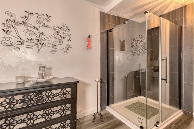 bathroom featuring a baseboard heating unit, baseboards, wood finished floors, and a shower stall