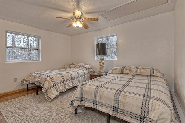 bedroom with attic access, wood finished floors, baseboards, and ceiling fan