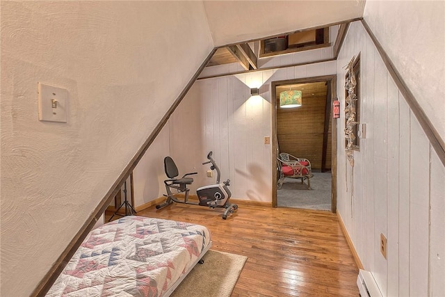 bedroom with wood walls, baseboards, and hardwood / wood-style floors