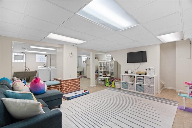 tiled living area with independent washer and dryer, a sink, a paneled ceiling, baseboards, and stairs