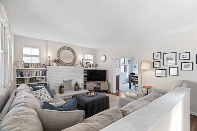 living area with baseboards, wood finished floors, and a fireplace