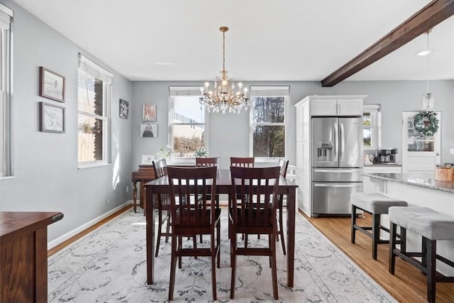 dining area with beamed ceiling, a notable chandelier, baseboards, and light wood finished floors