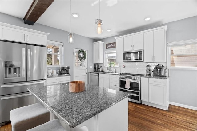 kitchen with backsplash, appliances with stainless steel finishes, white cabinetry, and dark wood-type flooring