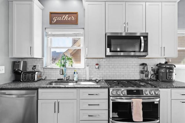 kitchen with dark stone countertops, decorative backsplash, appliances with stainless steel finishes, and white cabinets