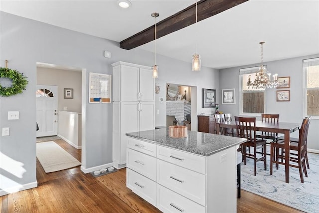 kitchen with beamed ceiling, white cabinets, stone countertops, and wood finished floors