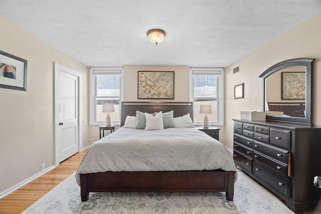 bedroom with visible vents, multiple windows, baseboards, and light wood-type flooring