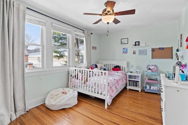 bedroom with ceiling fan, baseboards, and light wood-style floors