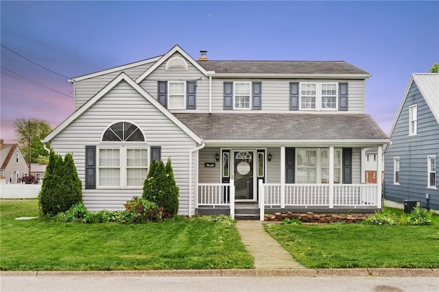 traditional-style house with a front lawn, a porch, and central AC