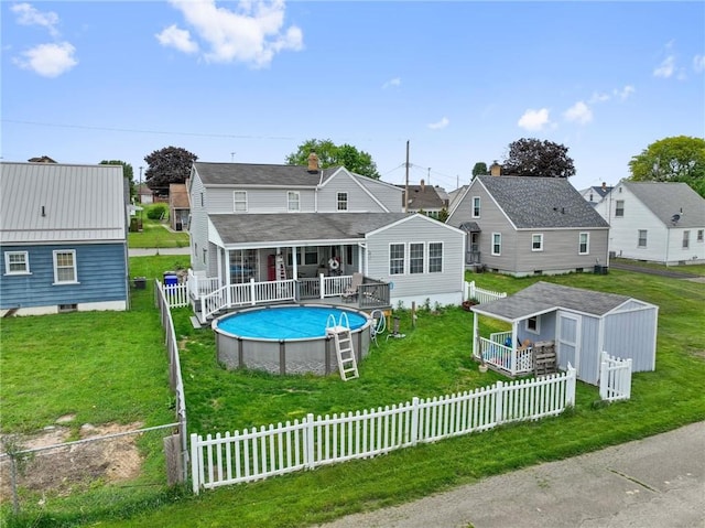 back of house featuring a fenced in pool, fence, roof with shingles, covered porch, and a lawn