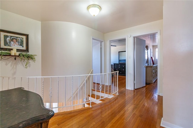 hall featuring baseboards, an upstairs landing, and hardwood / wood-style flooring