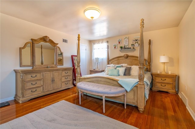 bedroom featuring visible vents, baseboards, and wood finished floors