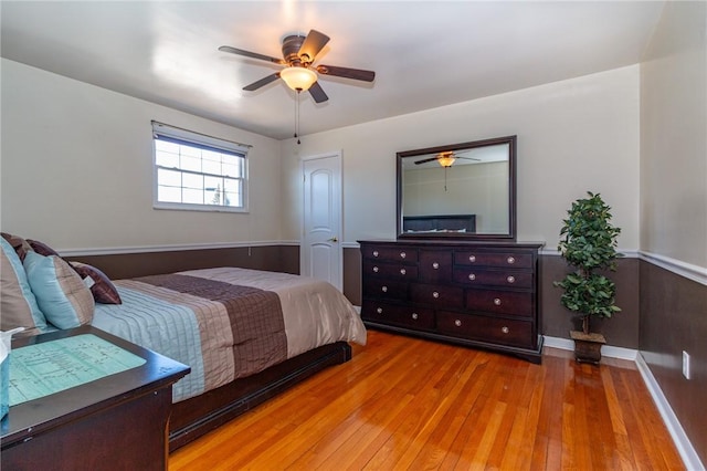 bedroom with a wainscoted wall, a ceiling fan, and wood-type flooring