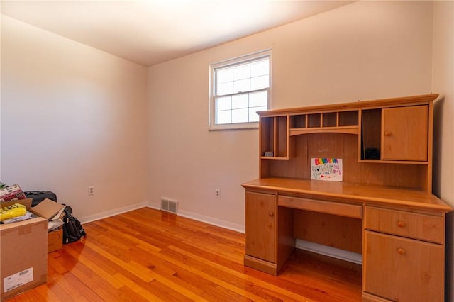 unfurnished office with baseboards, visible vents, and light wood finished floors