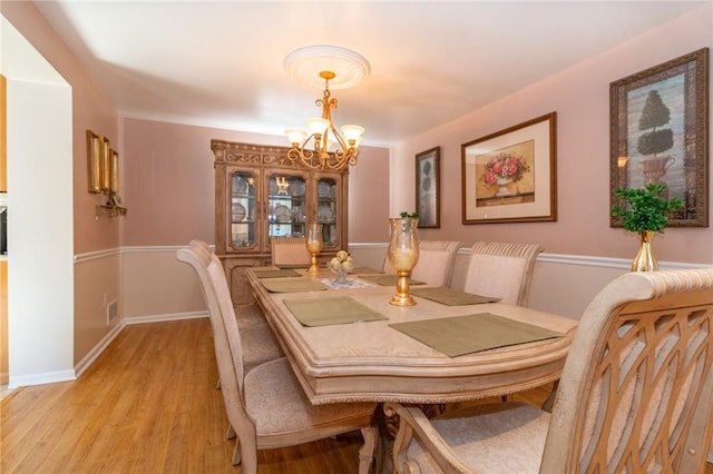 dining space featuring a chandelier, light wood-type flooring, and baseboards