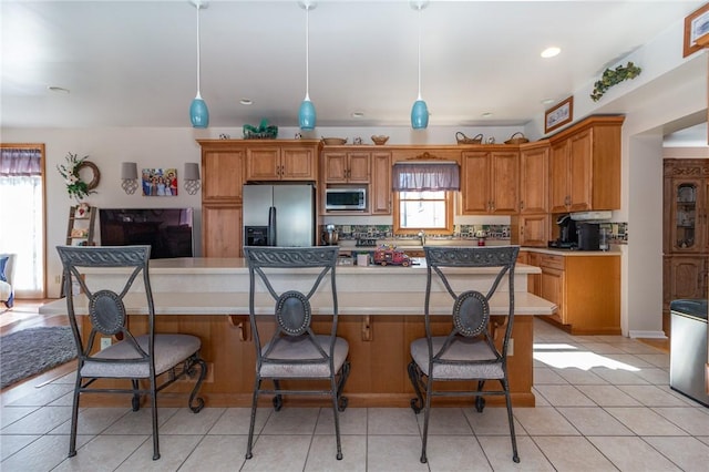 kitchen with a spacious island, a breakfast bar area, stainless steel appliances, and light countertops