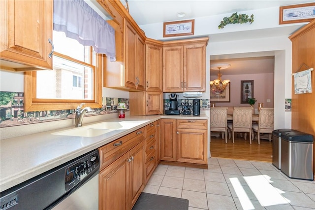 kitchen with a sink, stainless steel dishwasher, light countertops, light tile patterned floors, and a chandelier
