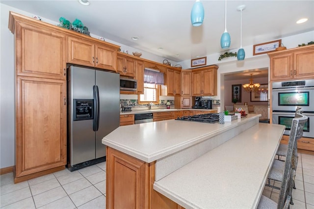 kitchen with a chandelier, light tile patterned flooring, appliances with stainless steel finishes, and a center island