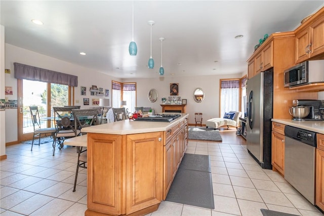kitchen with light tile patterned flooring, light countertops, appliances with stainless steel finishes, open floor plan, and a center island