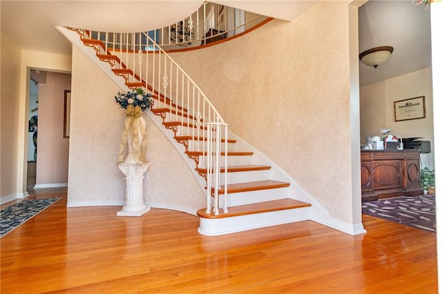 staircase with a high ceiling, baseboards, and wood finished floors