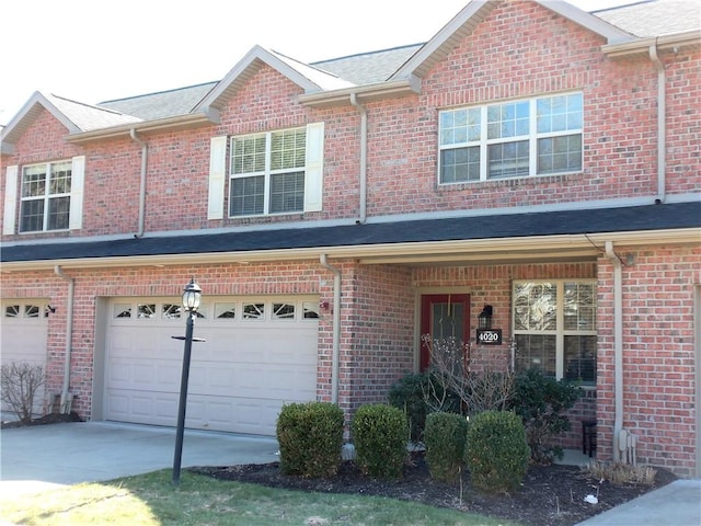 townhome / multi-family property with concrete driveway, an attached garage, and a shingled roof