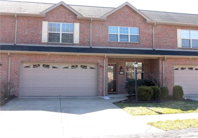 townhome / multi-family property with an attached garage, brick siding, and driveway