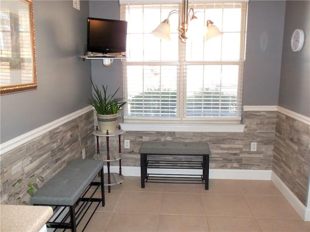 interior space with tile patterned flooring, tile walls, a wainscoted wall, and a chandelier