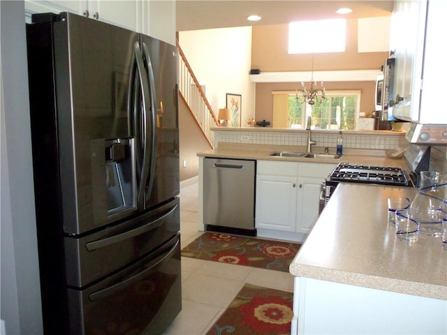 kitchen with decorative backsplash, appliances with stainless steel finishes, tile patterned floors, white cabinets, and a sink