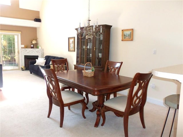 dining space featuring a notable chandelier, a fireplace, baseboards, and light carpet