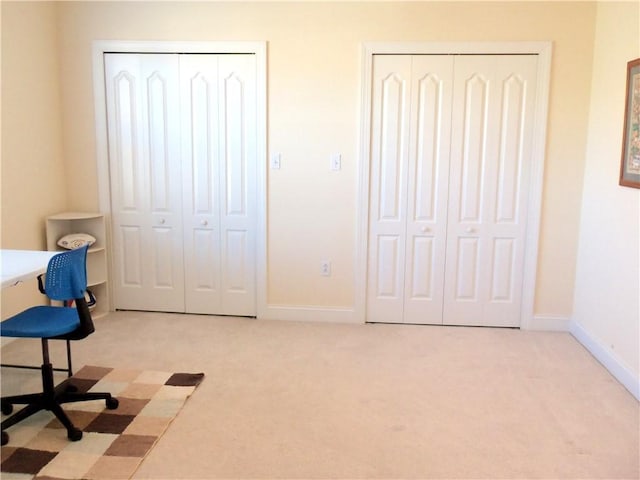 unfurnished office featuring baseboards and light carpet