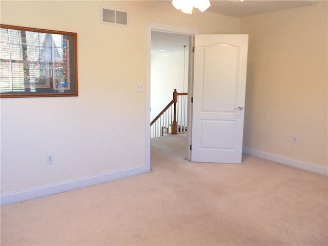 empty room featuring visible vents, light colored carpet, and baseboards