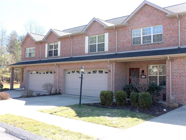 multi unit property with concrete driveway, an attached garage, and brick siding