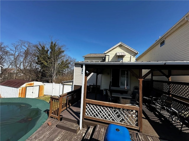 wooden deck with an outbuilding, a storage unit, and a fenced backyard