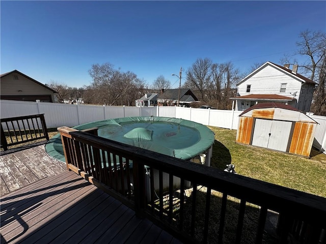 deck with a fenced in pool, a fenced backyard, an outdoor structure, a storage shed, and a lawn