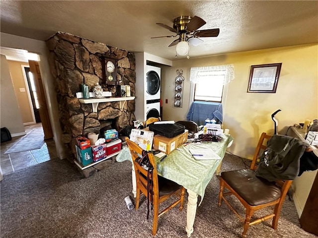 dining space with stacked washer and dryer, a textured ceiling, a fireplace, baseboards, and ceiling fan