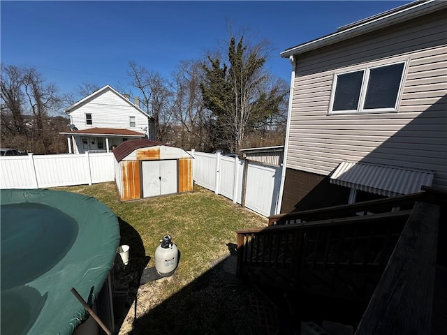 view of yard featuring a storage unit, an outdoor structure, a fenced backyard, and a gate