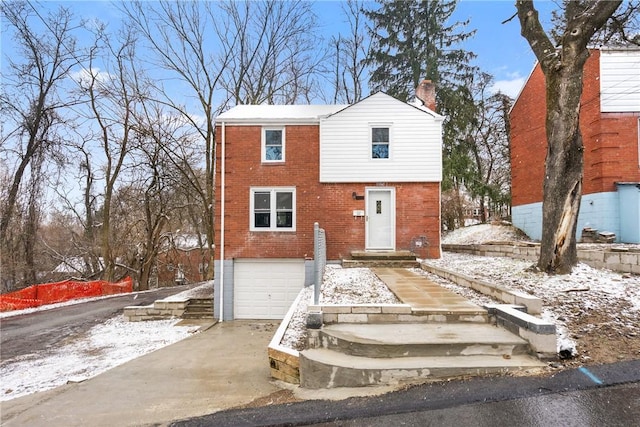 view of front of home with an attached garage, brick siding, driveway, and a chimney