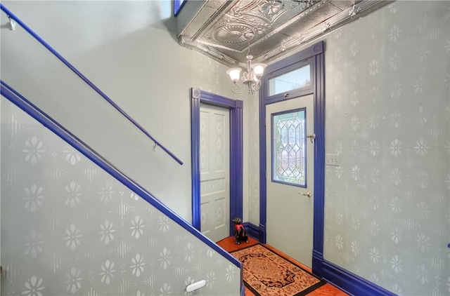 entryway with an inviting chandelier, wallpapered walls, and baseboards