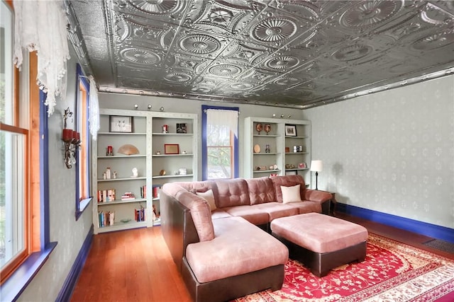 living room featuring a healthy amount of sunlight, an ornate ceiling, wallpapered walls, and baseboards