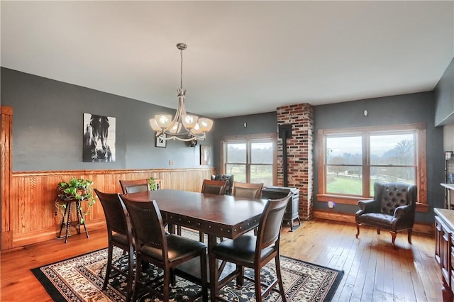 dining area with an inviting chandelier, light wood-type flooring, and wainscoting