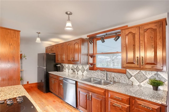 kitchen with a sink, stainless steel dishwasher, black electric stovetop, light wood-type flooring, and backsplash