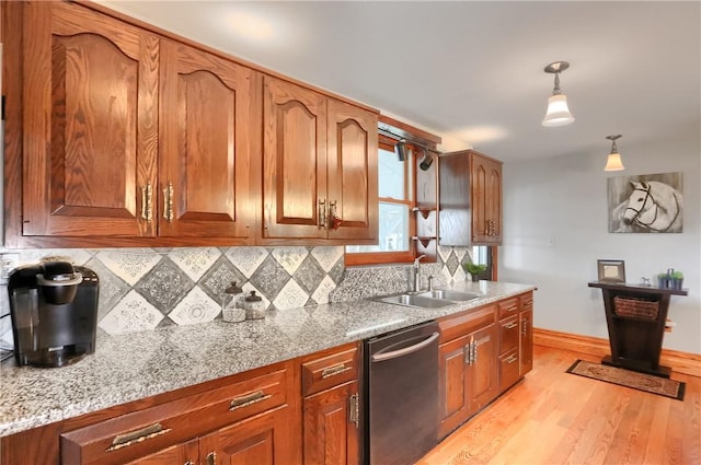 kitchen with a sink, pendant lighting, dishwasher, tasteful backsplash, and light wood-type flooring