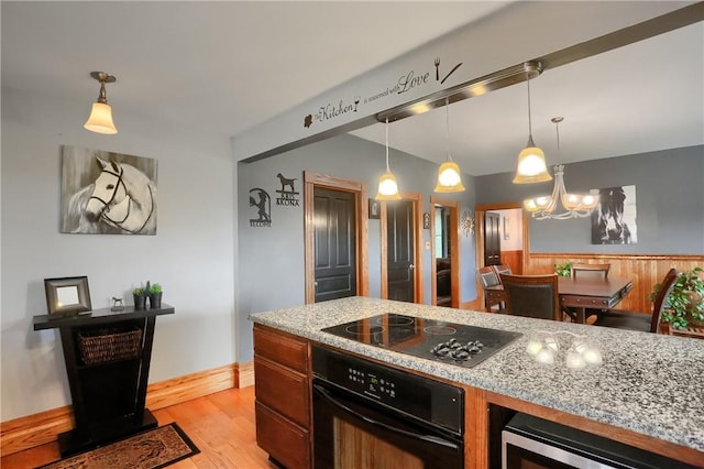 kitchen with light stone countertops, beverage cooler, light wood-type flooring, hanging light fixtures, and black appliances