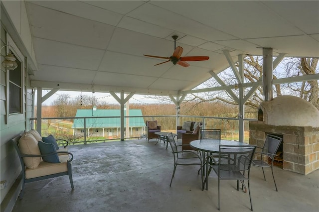 view of patio / terrace featuring outdoor dining area, a ceiling fan, and an outdoor fireplace