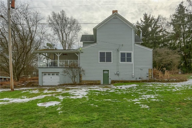 rear view of property featuring a balcony, a yard, an attached garage, a chimney, and ceiling fan