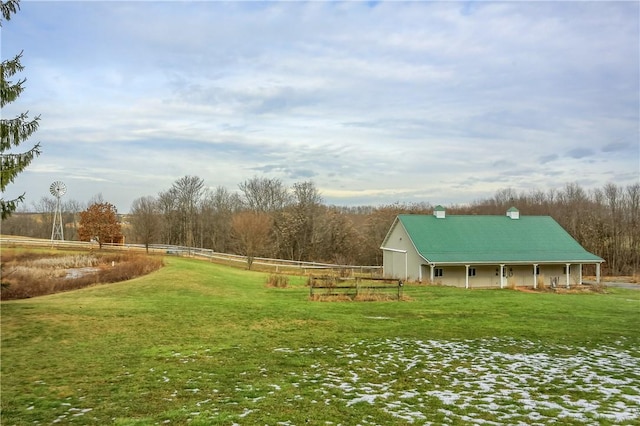 view of home's community with a rural view, a yard, and fence