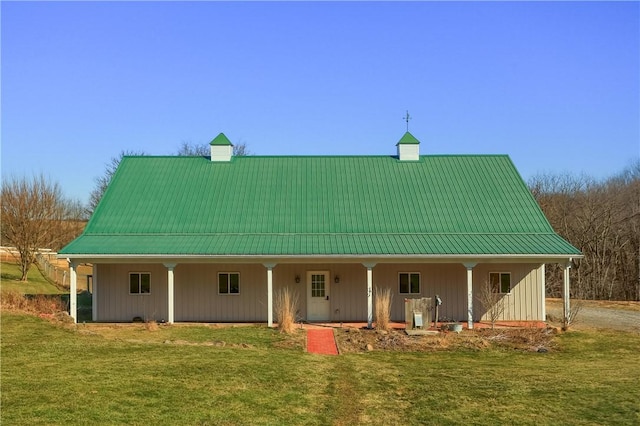 exterior space with a chimney, covered porch, metal roof, and a yard